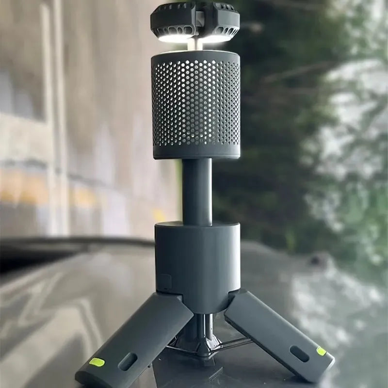 Compact telescopic camping lantern on tripod base placed on a reflective surface outdoors with blurred background.