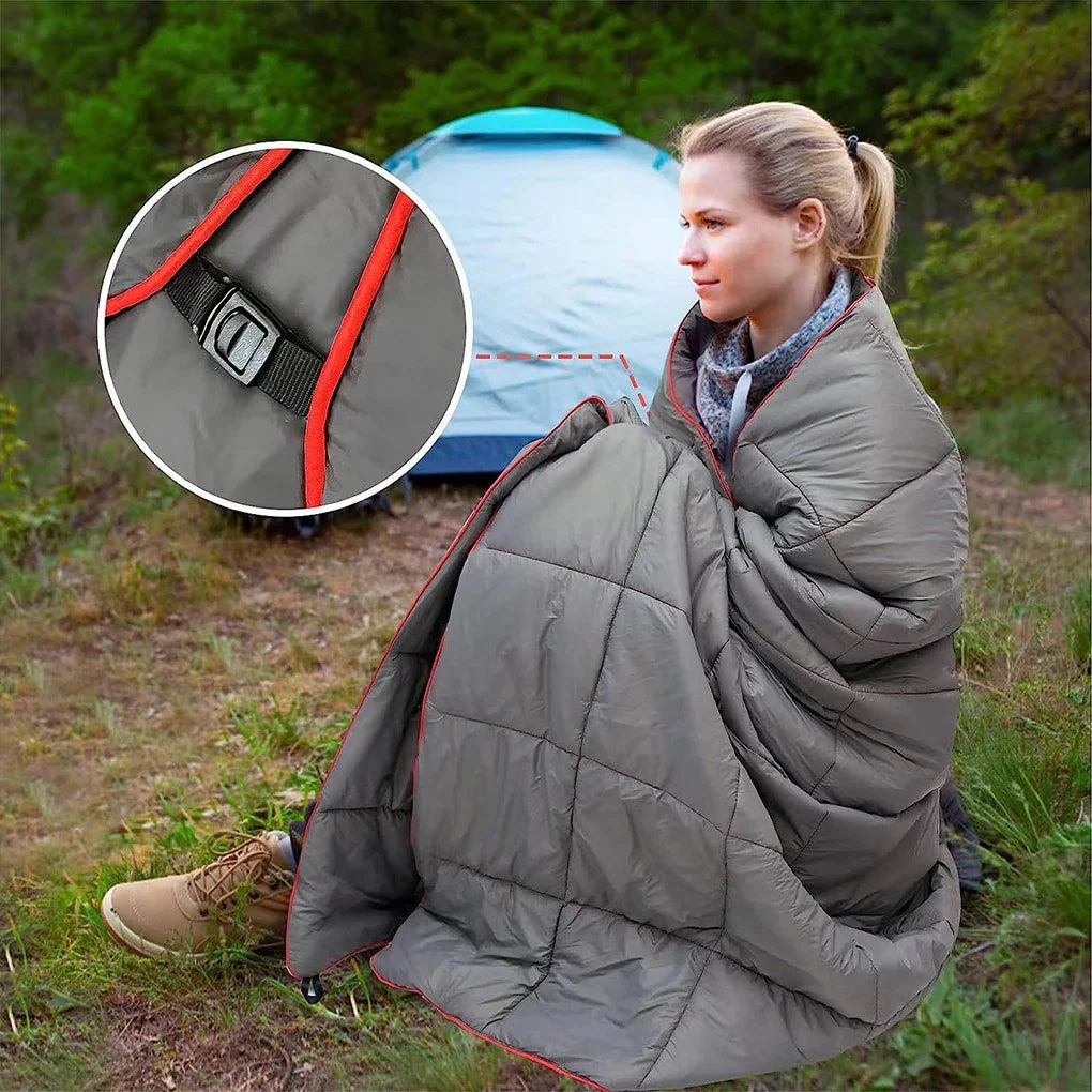 Woman sitting on the ground near a tent wrapped in the Adventure Cozy Puff Ultralight Blanket with close-up of buckle strap