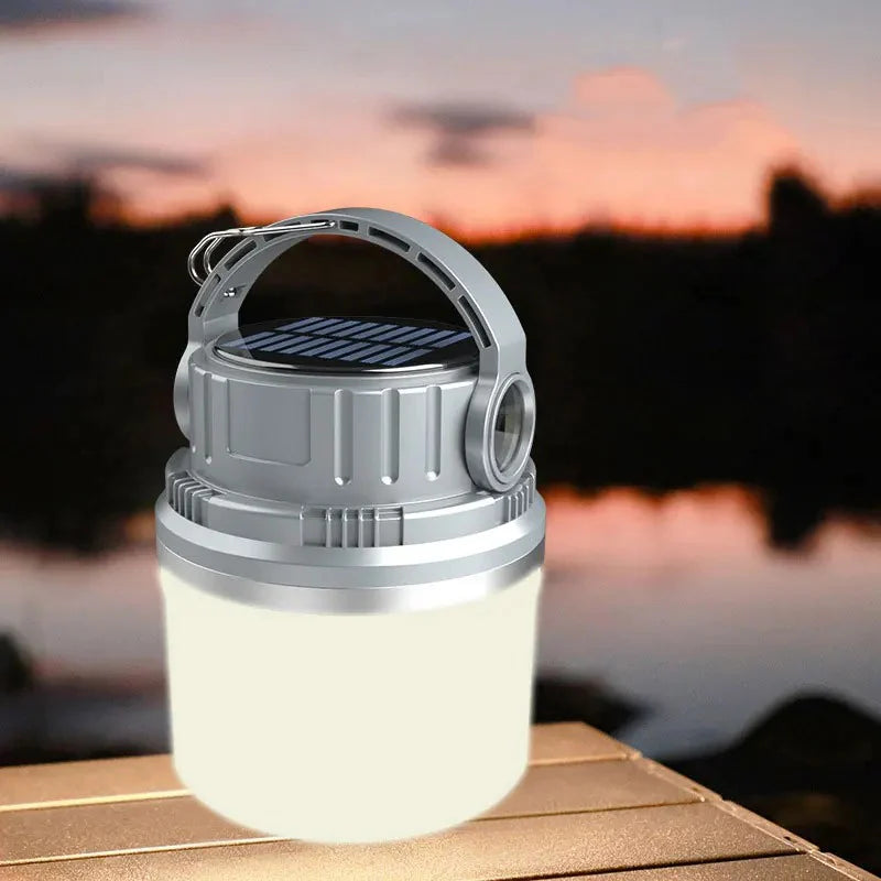 LED Adventure Light glowing softly on a wooden table with a blurred sunset background, showing its compact design