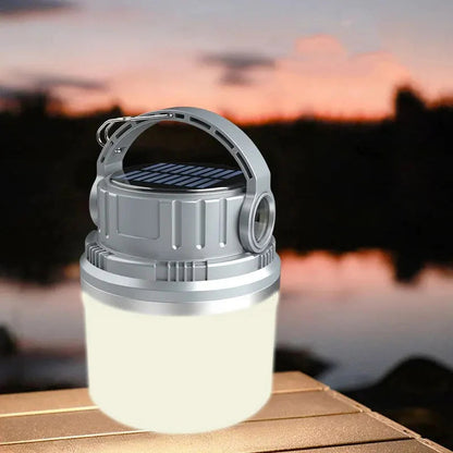 LED Adventure Light glowing softly on a wooden table with a blurred sunset background, showing its compact design