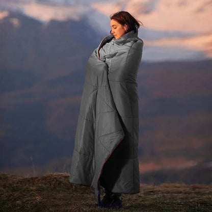 Woman standing outdoors in the mountains wrapped in the Adventure Cozy Puff Ultralight Blanket